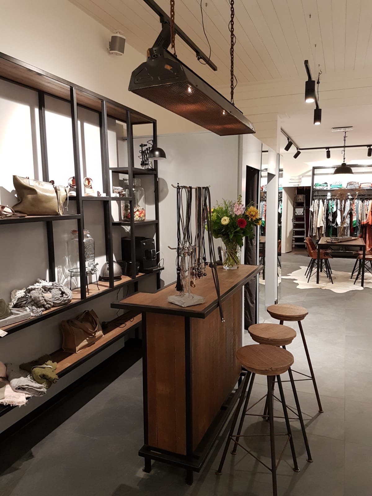 Zicht op een winkel met een houten bar, barkrukken en spots aan het plafond